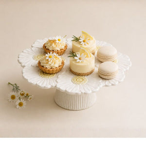 Assorted small desserts on a white ceramic cake stand with a light background