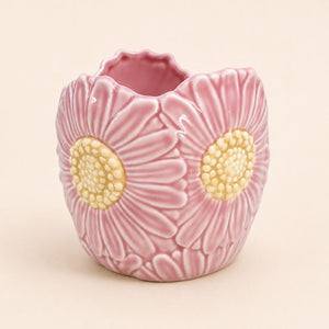 Pink ceramic vase with floral design on a beige background