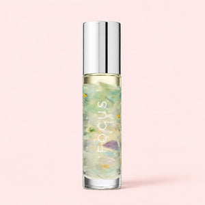 Focus essential oil roller with silver cap and fluorite crystals in clean aesthetic product setup