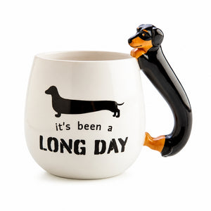A Furever Pets Dachshund 3D Handle Mug with the text 'It's been a LONG DAY' on the front, featuring a 3D black and orange dachshund dog handle.
