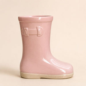 Pink rain boot with a buckle on a beige background