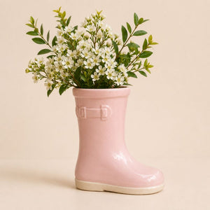 Pink rain boot with a bouquet of white flowers on a beige background