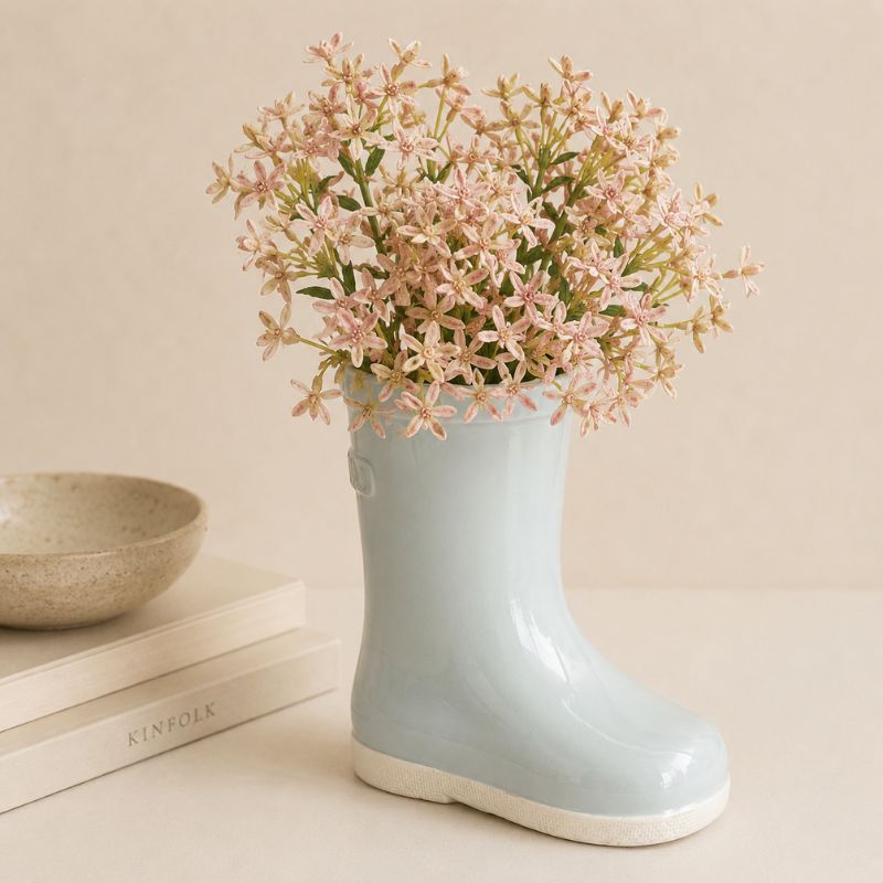 Light blue rubber boot with pink flowers on a beige surface