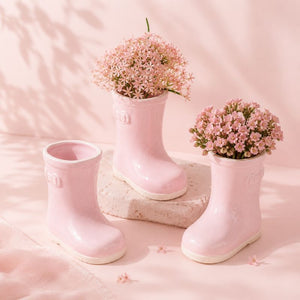 Pink gumboots with small pink flower arrangements on a soft pink background