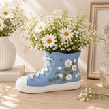 Gym Boot Resin Vessel Blue 11cm filled with flowers on a wooden surface.