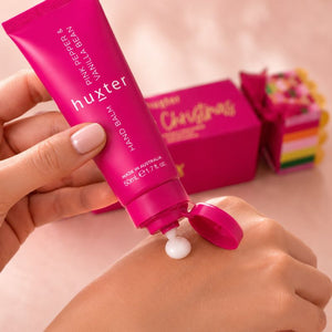 Huxter 50ml Pink Pepper and Vanilla Bean hand balm dispensed onto a woman's hand