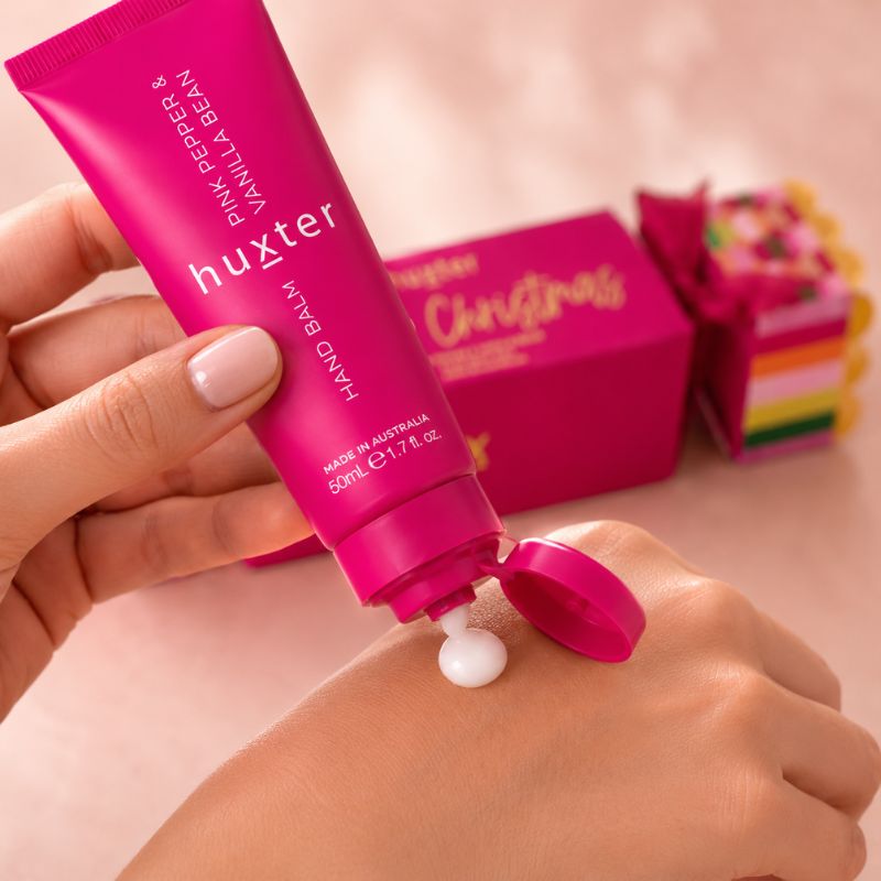 Huxter 50ml Pink Pepper and Vanilla Bean hand balm dispensed onto a woman's hand