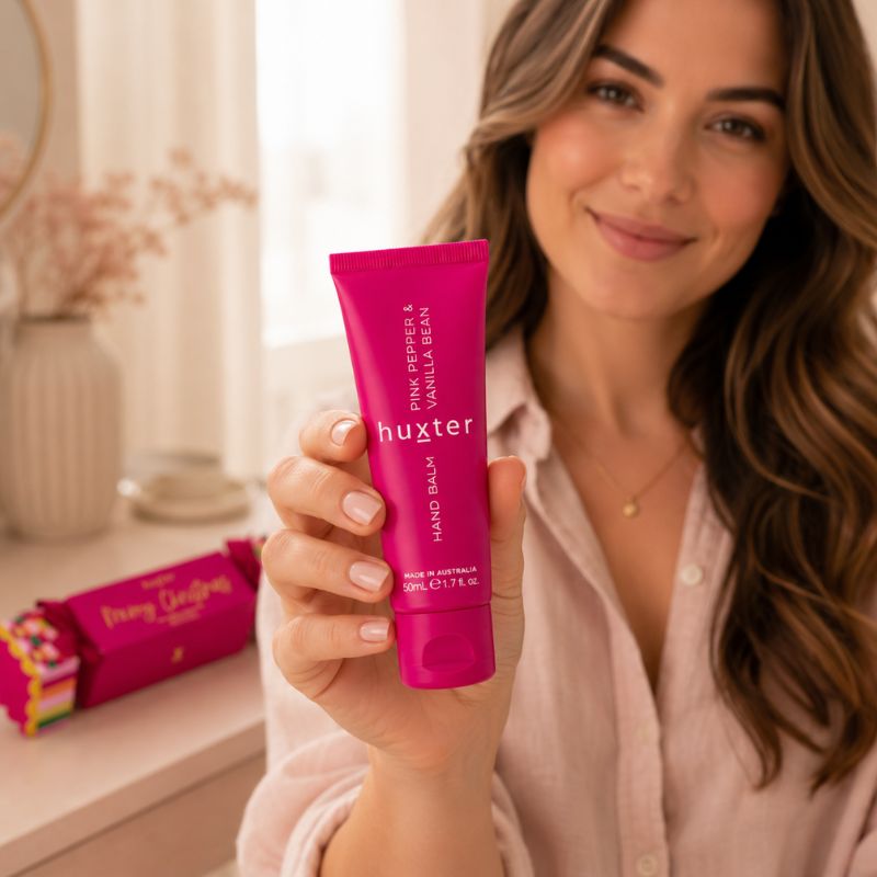 Woman holding Huxter 50ml Pink Pepper and Vanilla Bean hand balm toward the camera
