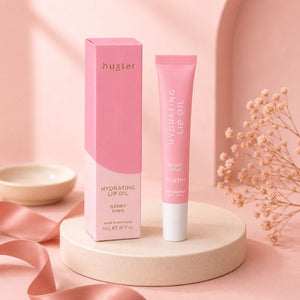 Huxter Berry Pink Hydrating Lip Oil with matching box on cream pedestal in blush studio setting
