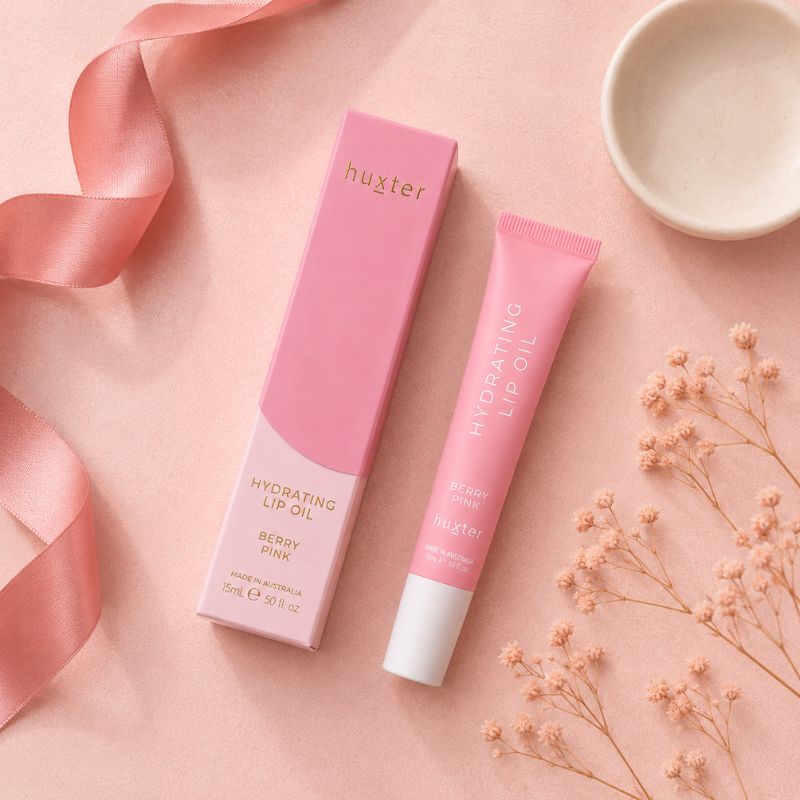 Huxter Berry Pink Hydrating Lip Oil tube and matching box in overhead blush pink flat lay