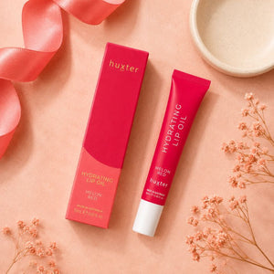 Huxter Melon Red Hydrating Lip Oil tube and matching box in overhead coral blush flat lay