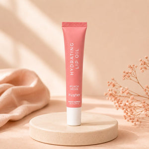 Huxter Peach Nude Hydrating Lip Oil tube on cream pedestal