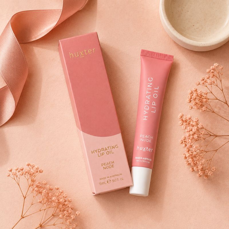 Huxter Peach Nude Hydrating Lip Oil tube and box in overhead blush flat lay