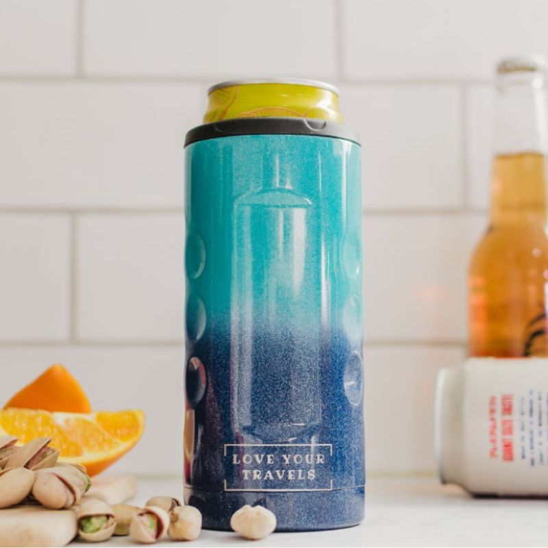 Blue thermos with 'Love Your Travels' text on a kitchen counter with oranges and nuts.