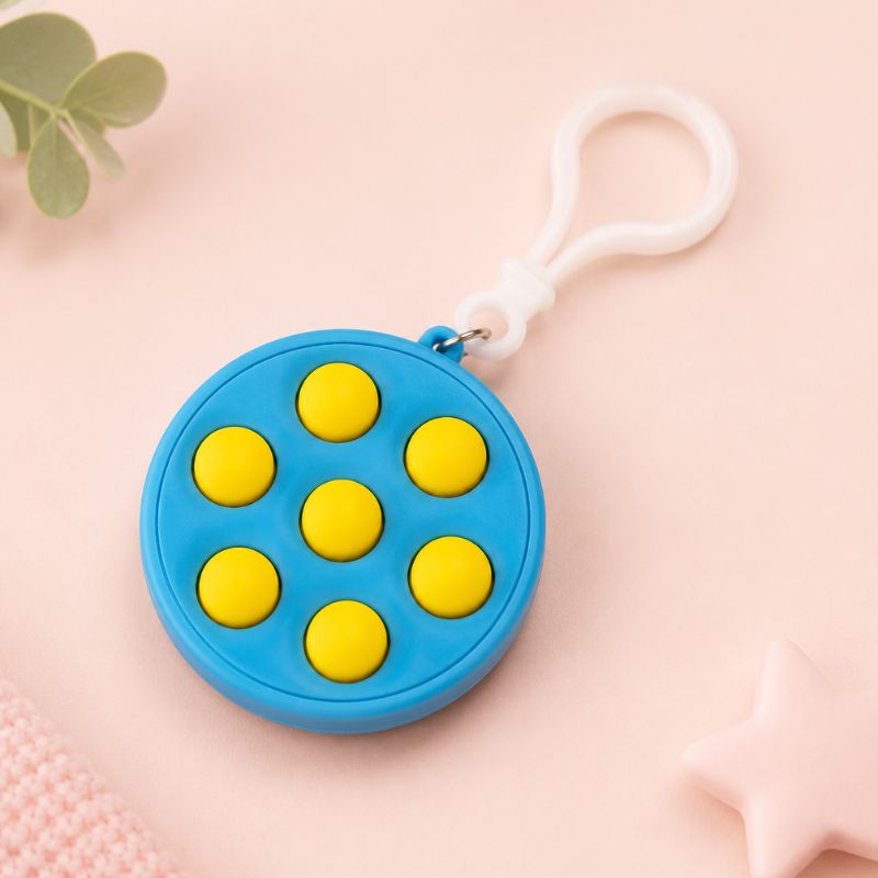 Blue fidget toy with yellow dots and a white clip on a pink background