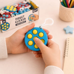 Person holding a blue fidget clicker with yellow buttons, packaging in the background.