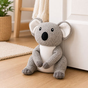Plush koala toy door stopper on a wooden floor with a blurred background