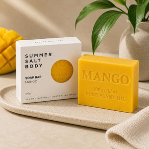 Mango Soap Bar - 100g and packaging labeled 'Summer Salt Body' on a beige surface with a plant in the background.