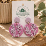 Mauve Flower Dangle Earrings on a 'Love Shack Giftware' card with plants in the background