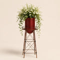 Metal garden water tower planter with cascading white flowers on a light beige background.