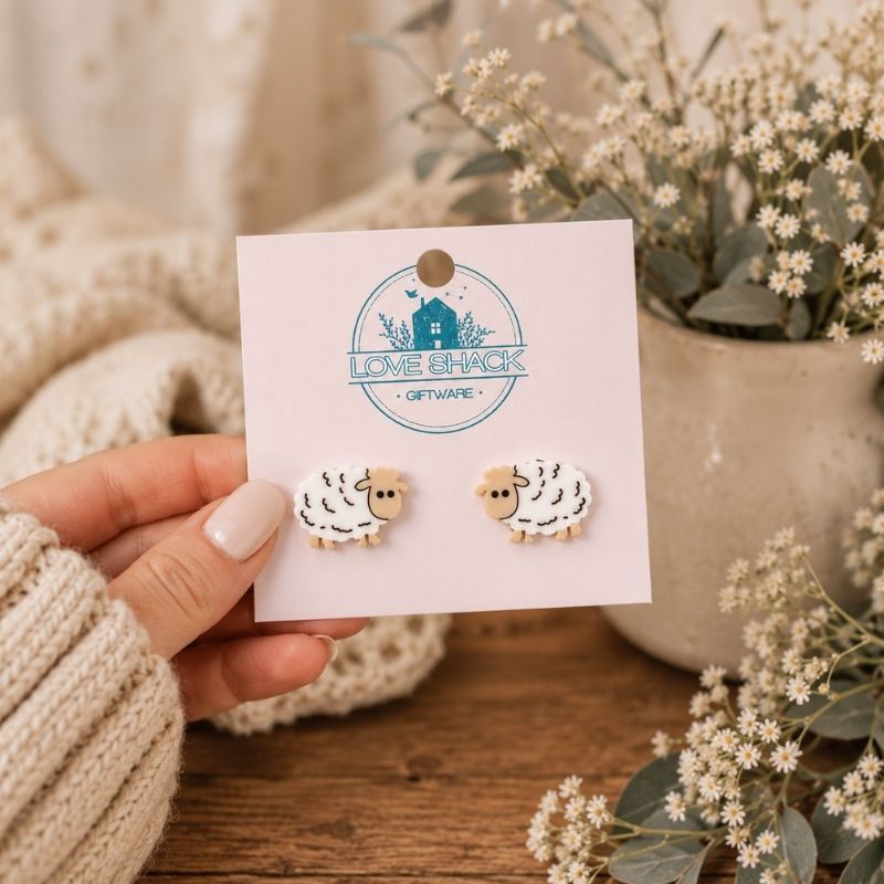 Mini Sheep Stud Earrings on a 'Love Shack Giftware' card held by a hand with a neutral background.