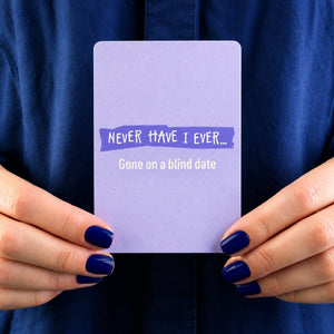 Person holding a Never Have I Ever card against a dark blue background