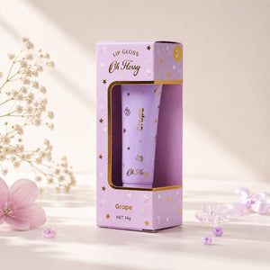 Oh Flossy Grape Natural Lip Gloss for Kids with lavender packaging in a soft floral setting
