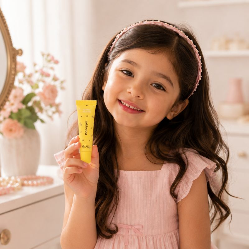 Young girl holding Oh Flossy Natural Pineapple Lip Gloss for Kids