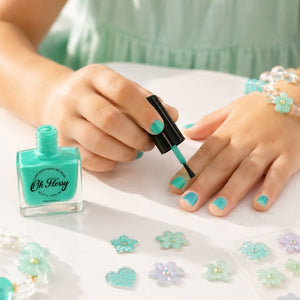 Applying Oh Flossy Aqua Kids Nail Polish to a child's fingernail