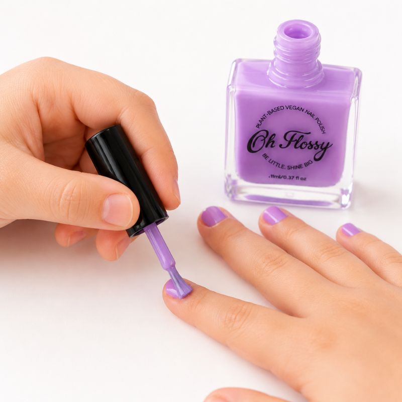 Close-up of hand applying Oh Flossy purple kids nail polish