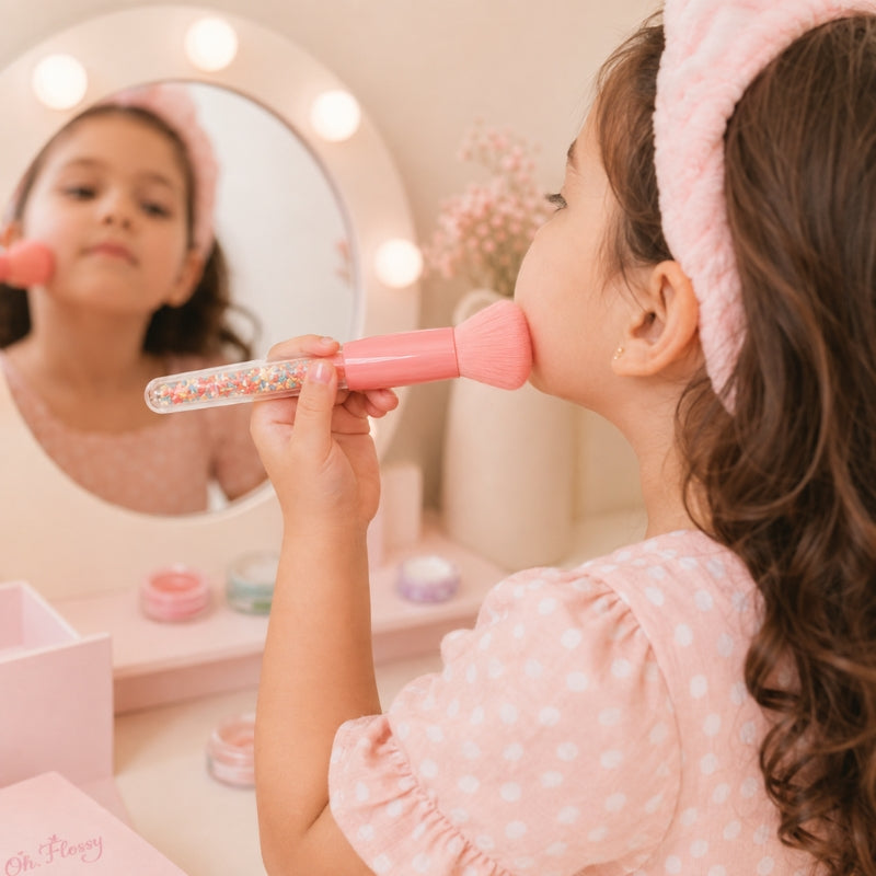Young girl applying makeup with Oh Flossy Sprinkle Makeup Brush at a vanity