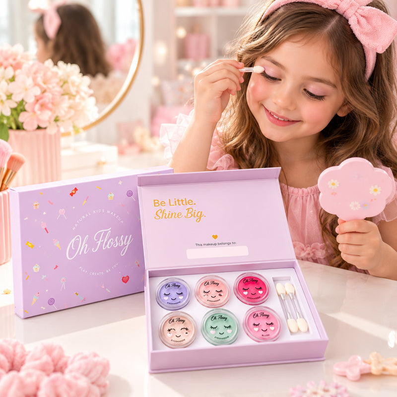 Young girl applying Oh Flossy Sweet Treat kids eyeshadow at a pink vanity with the natural makeup set and mirror.