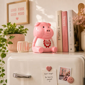 Pink piggy bank on a shelf with books and decorative items
