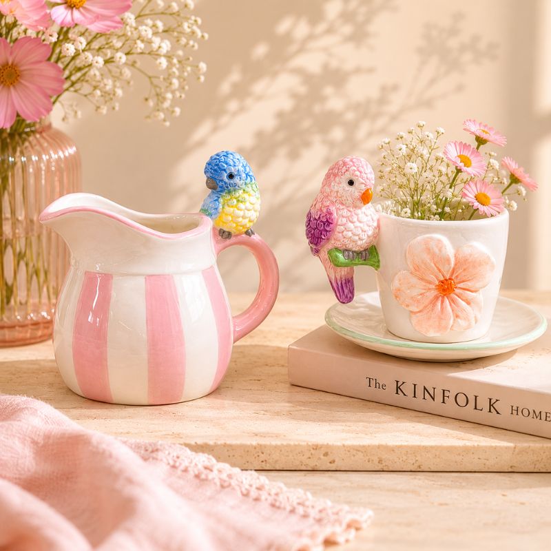 Decorative ceramic pitcher with striped design, bird-shaped candle holder, and flowerpot on a wooden surface._Loveshack Giftware