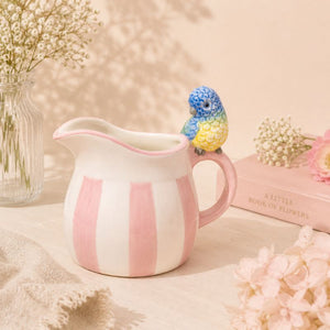 Pink and white striped ceramic pitcher with a colorful bird figurine on a soft beige background.-Loveshack Giftware