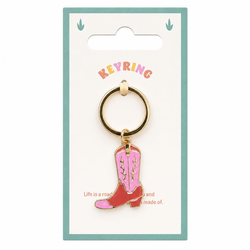 A Pink Cowboy Boot Enamel Keyring on a white card backing. The keyring features a gold-tone metal ring and a dangling charm shaped like a pink and red cowboy boot with white stitching, set against a white background with a teal border.