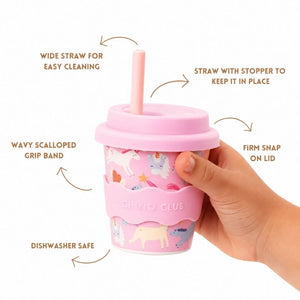 Pink Unicorn Babychino Cup is held by a hand, featuring text on features.