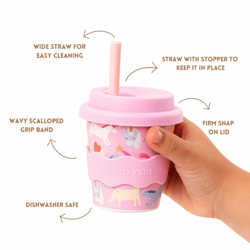 Pink Unicorn Babychino Cup is held by a hand, featuring text on features.
