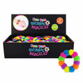A black display box filled with brightly colored pom-pom squishy bracelets, with one matching bracelet shown outside the box on the right. The box has colorful branding that reads 'Pom Pom Squishy Bracelet.