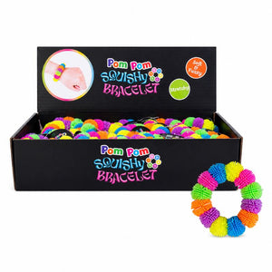 A black display box filled with brightly colored pom-pom squishy bracelets, with one matching bracelet shown outside the box on the right. The box has colorful branding that reads 'Pom Pom Squishy Bracelet.