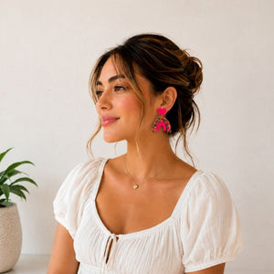 Woman wearing a white blouse with Pop Rainbow Dangle Earrings against a plain background
