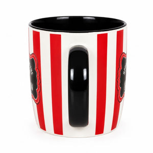 A white ceramic mug with bold red vertical stripes, a glossy black handle, and a black interior, featuring decorative black labels with red borders on the sides.