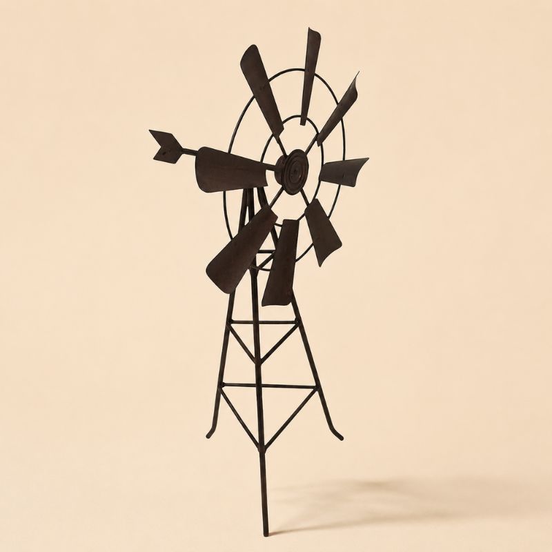 Rustic metal garden windmill stake on a light beige background with soft shadow, farmhouse garden décor accent.