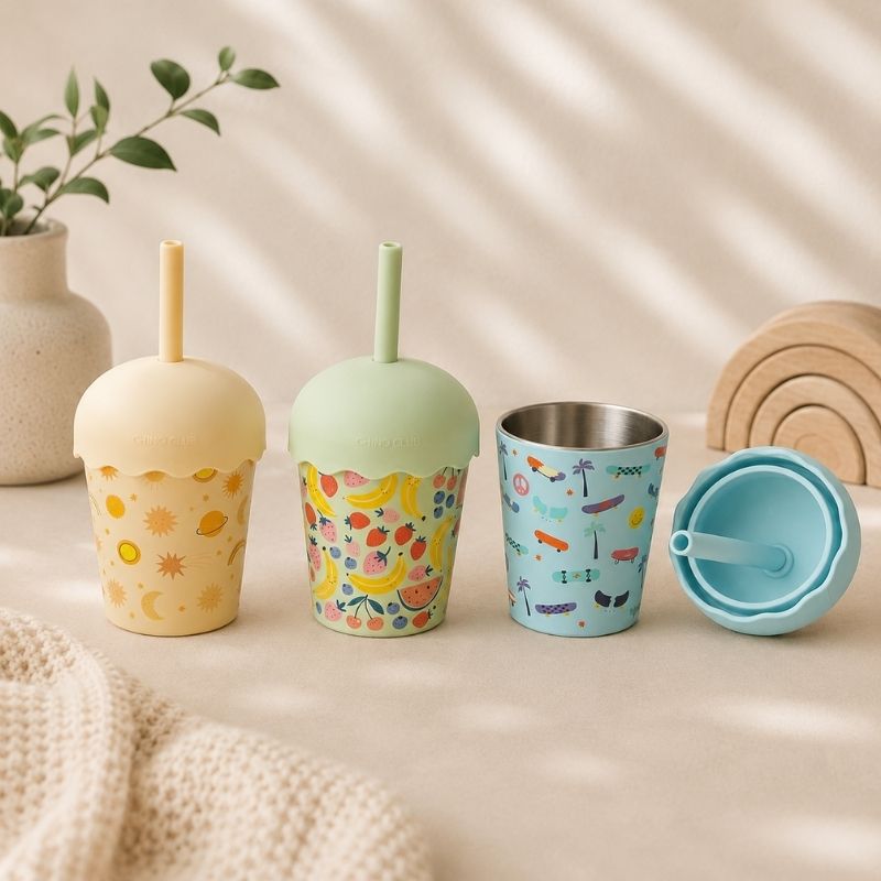 Set of colorful children's cups with straws on a neutral background