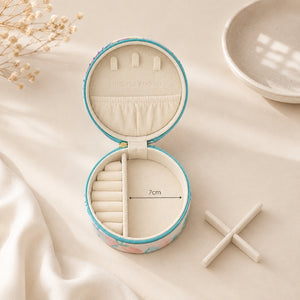A Small Jewellery Case – Haven with a pastel floral pattern and turquoise trim, shown on a soft cream fabric background. The inside has cream fabric lining with ring rolls and a divider, plus a printed measurement marker reading 7cm.