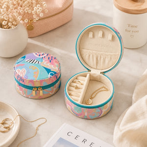 Two Small Jewellery Cases – Haven with a colorful abstract pattern in pink, blue, and beige, displayed on a light marble surface. One box is closed, and the other is open to show its cream-colored interior with ring slots and small pouches, styled with gold jewelry and decorative props.