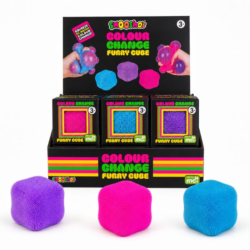 A retail display box of mdf Coooloo Colour Change Furry Cube toys, with three colorful furry cubes in purple, pink, and blue displayed in front of the black packaging on a white background.