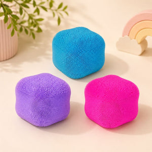 Smoosho's Colour Change Furry Cube in bright blue, purple, and hot pink, arranged on a light beige surface with soft decorative background elements.