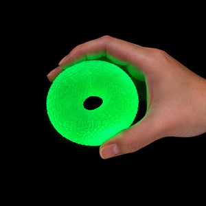 A hand holding a glowing neon green donut-shaped textured ball against a solid black background.