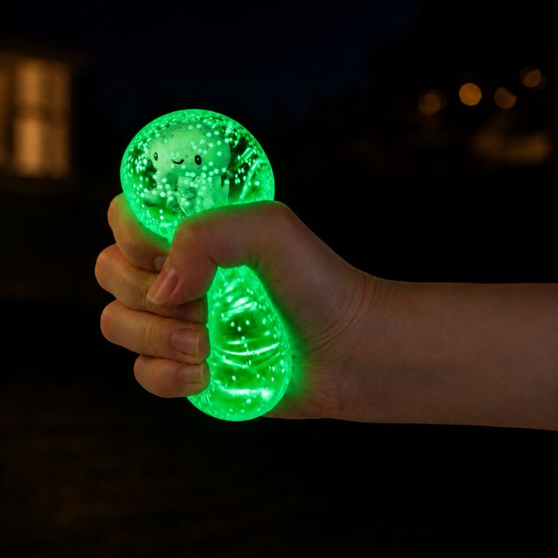 Glowing green sea animal squishy toy being squeezed by hand in the dark